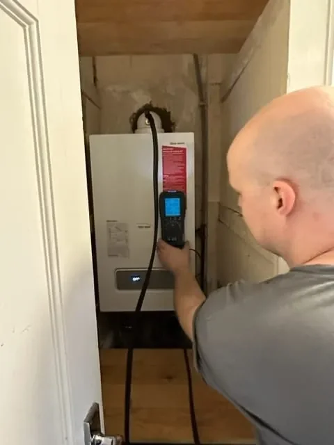 Engineer checking a boiler with a flue gas analyser