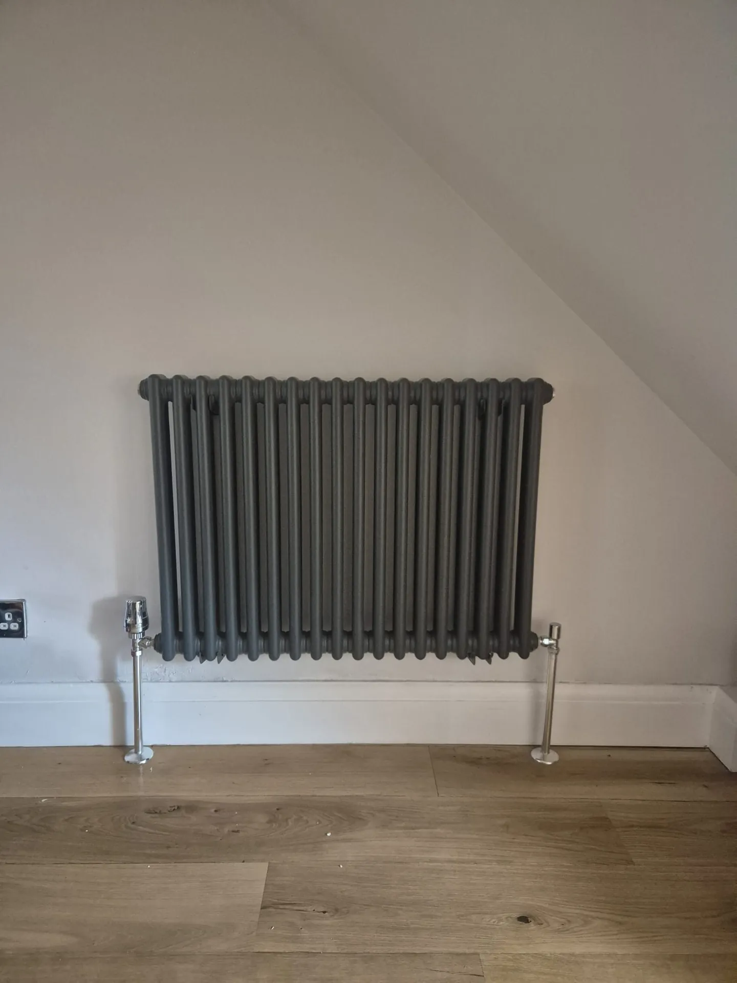 Dark column radiator fitted in a Romford living room